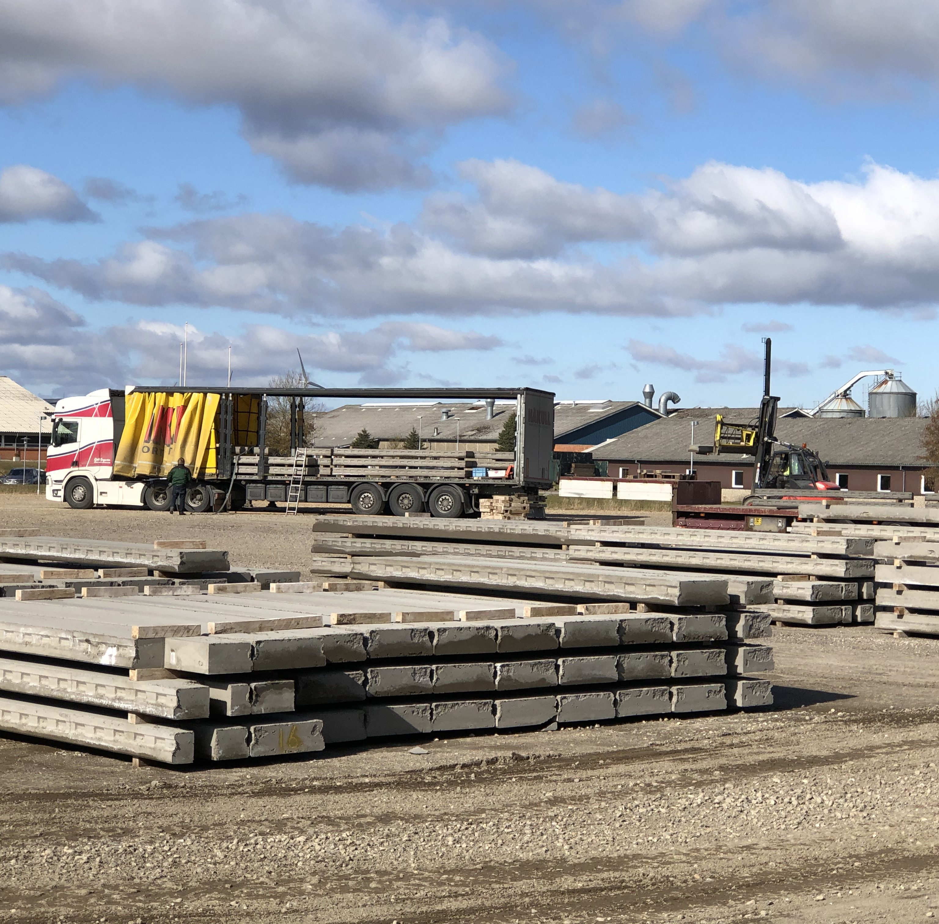 Lastbil og medarbejdere på byggeplads med beton elementer